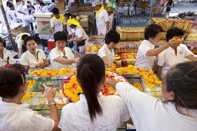 People pay their respects to the remains of unclaimed bodies during a buddhist ceremony at the Poh Teck Tung Foundation Cemetery in Samut Sakhon province, Thailand, November 11, 2015. Human remains from 3,890 unclaimed bodies have been dug out of graves to be cleaned and put into storage in a warehouse before being cremated, in order to make room for further unidentified corpses, according to the Poh Teck Tung Foundation. (Photo by Athit Perawongmetha/Reuters)