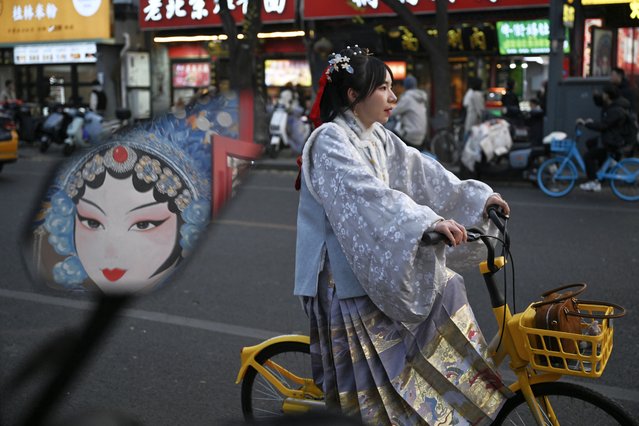 A woman wears a traditional Chinese costume as she rides a bicycle along the street in Beijing on November 23, 2025. (Photo by Pedro Pardo/AFP Photo via Getty Images)