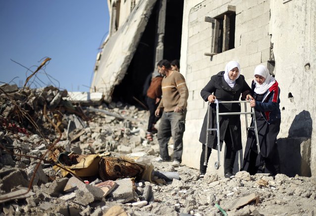 Palestinian girl Manar Al-Shinbari (2nd R), 15, who lost her both legs by what medics said was Israeli shelling at a UN-run school where she was taking refuge during the 50-day war last summer, uses her walker at the ruins of her house that witnesses said was destroyed by Israeli shelling during the war, in Biet Hanoun in the northern Gaza Strip January 13, 2015. (Photo by Mohammed Salem/Reuters)