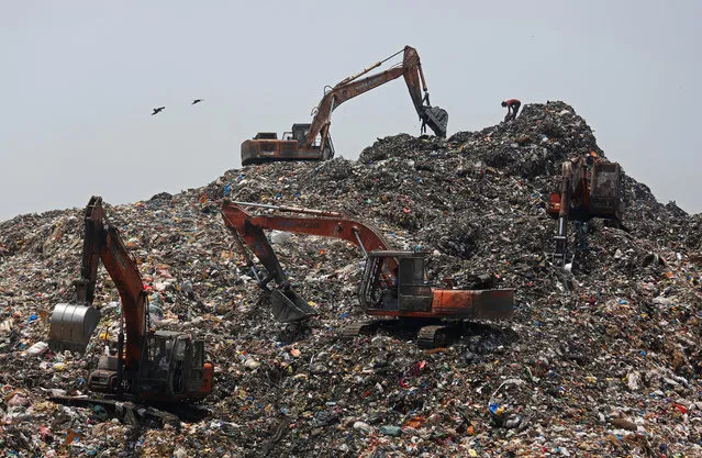 Bulldozers pile up garbage at a dumping ground on the outskirts of Mumbai, India, April 16, 2018. (Photo by Francis Mascarenhas/Reuters)