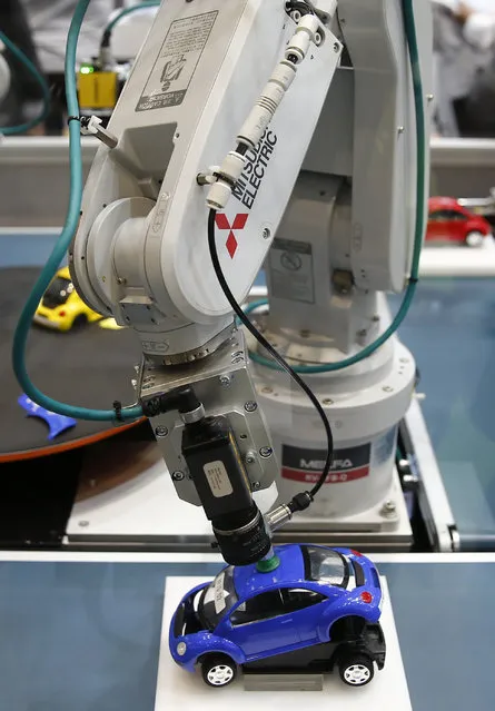 A robot arm by Mitsubishi Electric assembles a toy car at the System Control Fair SCF 2015 in Tokyo, Japan December 2, 2015. (Photo by Thomas Peter/Reuters)