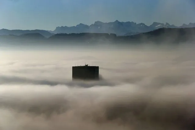 The top of Switzerland's highest skyscaper the Prime Tower (126 metres /413 ft) peeps through the fog in front of the Swiss Alps, early morning in Zurich, Switzerland December 7, 2015. (Photo by Arnd Wiegmann/Reuters)