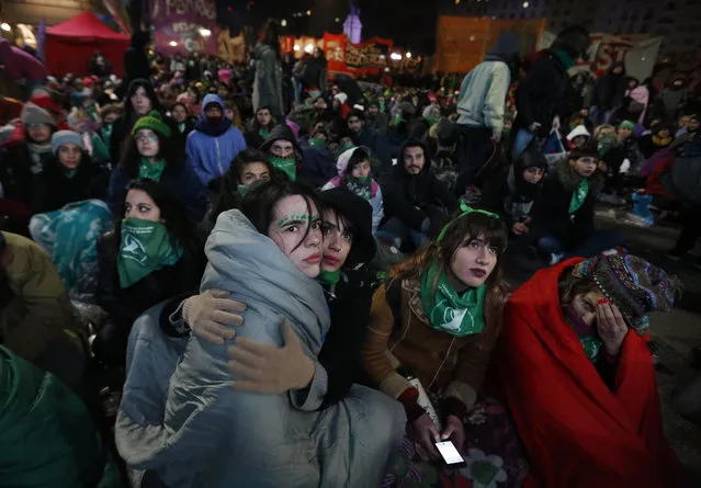In this early morning Thursday, June 14, 2018 photo, women watch on a big screen lawmakers vote on a bill that would legalize abortion, in Buenos Aires. The lower house of Argentina's congress went on to approve a bill that would legalize elective abortion in the first 14 weeks of pregnancy, sending the measure to the Senate. (Photo by Jorge Saenz/AP Photo)