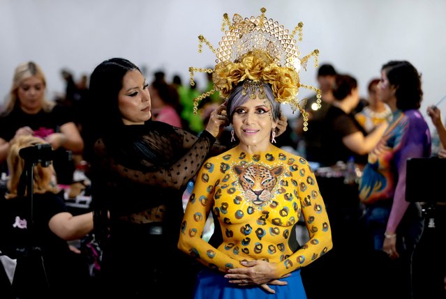 A breast cancer survivor stands while an artist places a headdress on her during the ninth edition of the project “Una pincelada por la vida” (A brushstroke for life), in Zapopan, Jalisco state Mexico, on September 8, 2024. “Una pincelada por la vida” is an altruistic project involving more than 100 women survivors with the aim to raise awareness of breast cancer in the world. (Photo by Ulises Ruiz/AFP Photo)