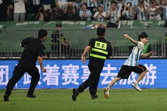 A pitch invader runs to evade the security personnel during a friendly football match between Australia and Argentina at the Workers' Stadium in Beijing on June 15, 2023. (Photo by Pedro Pardo/AFP Photo)