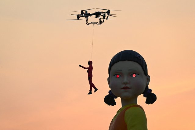 A 12 meter-tall statue of Young-hee, the iconic doll from Netflix's South Korean TV series “Squid Game”, is seen on a barge in front of Wat Arun temple ahead of the launch of Season 2, in Bangkok on December 19, 2024. (Photo by Lillian Suwanrumpha/AFP Photo)