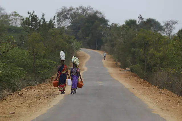 Indian villagers carry their belongings on their heads and walk towards their village on the outskirts of Hyderabad, India, Friday, February 19, 2021. (Photo by Mahesh Kumar A./AP Photo)