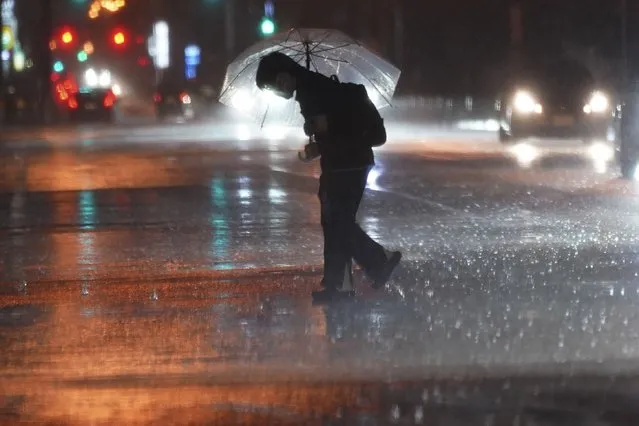 A person holds an umbrella against strong wind and rain as he walks on a street Friday, June 2, 2023, in Tokyo, as a tropical storm was approaching. (Photo by Eugene Hoshiko/AP Photo)