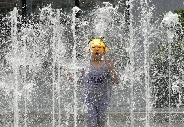 A boy cools off in a public fountain in Seoul, South Korea, Monday, June 19, 2023. A heat wave warning was issued in Seoul as temperatures soared above 34 degrees Celsius (93 degrees Fahrenheit) Monday. (Photo by Ahn Young-joon/AP Photo)