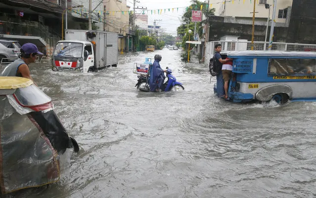 Commuters ride to work amidst flooding in Manila, Philippines, after overnight Southwest monsoon rains brought about by tropical storm Ampil inundated low-lying areas in Metropolitan Manila and nearby provinces Friday, July 20, 2018. Heavy rains continue to flood Manila forcing authorities to suspend classes for the third straight day Friday. (Photo by Bullit Marquez/AP Photo)
