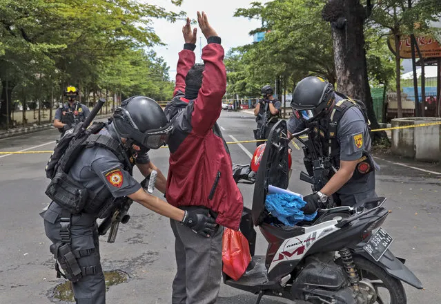 Police officers search a man at a security checkpoint near the site of Sunday's suicide bomb attack at the Sacred Heart of Jesus Cathedral in Makassar, South Sulawesi, Indonesia, Monday, March 29, 2021. (Photo by Yusuf Wahil/AP Photo)