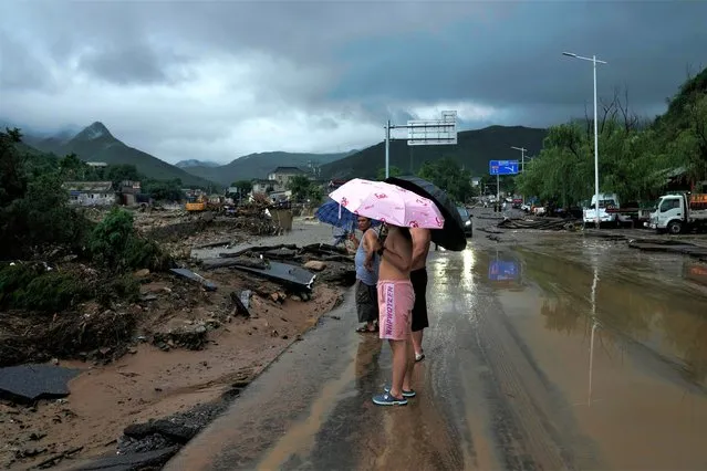 People look at a riverbank and road damaged by floodwaters in the Mentougou district as continuous rain fall triggers alerts in Beijing, Monday, July 31, 2023. (Photo by Andy Wong/AP Photo)