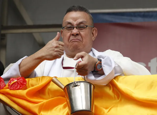 A priest gestures after he ran out of holy water to be sprinkled to devotees and their religious statues (not pictured) two days before the annual procession of the Black Nazarene in Manila, Philippines January 7, 2016. (Photo by Erik De Castro/Reuters)