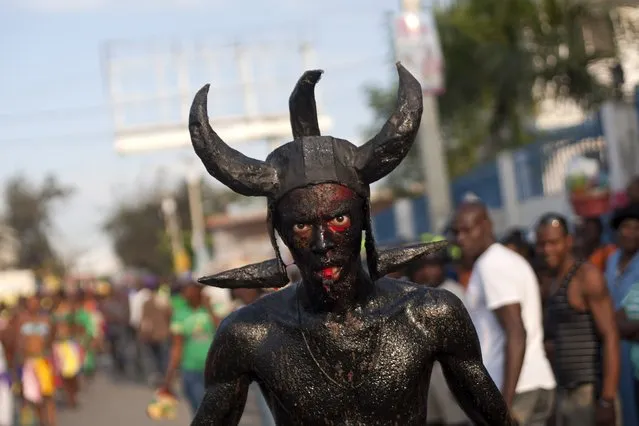 A man, decked out with horns and his body smothered in clay mud and oil, marches in a Carnival parade to the national palace, in Port-au-Prince, Haiti, Monday, February 16, 2015. (Photo by Dieu Nalio Chery/AP Photo)