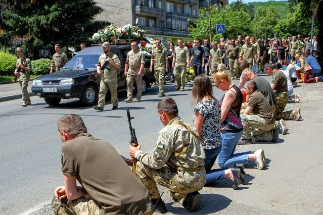 Local residents kneel during a funeral procession of a senior (first) lieutenant Vasyl Herych, 31, a service member of the 15th Separate Mountain Assault Battalion, who was killed in a fight during Russia's invasion, in Perechyn, Zakarpattia region, Ukraine on June 8, 2022. (Photo by Serhii Hudak/Reuters)