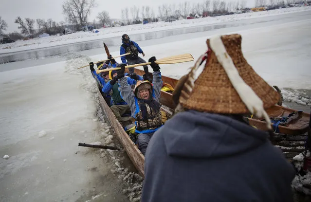 In this Thursday, December 1, 2016 photo, Virginia Redstar of Colville, Wash., and a member of the Colville Native American tribe, celebrates upon reaching shore by canoe at the Oceti Sakowin camp where people have gathered to protest the Dakota Access oil pipeline in Cannon Ball, N.D. Redstar traveled from Montana with fellow tribal members on canoe for 10 days down the Missouri river to reach the camp. (Photo by David Goldman/AP Photo)