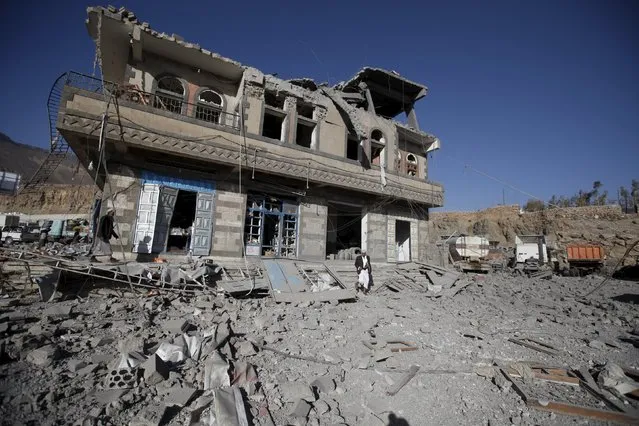 People walk next to a damaged building at the site of a Saudi-led air strike in Yemen's capital Sanaa January 4, 2016. (Photo by Khaled Abdullah/Reuters)