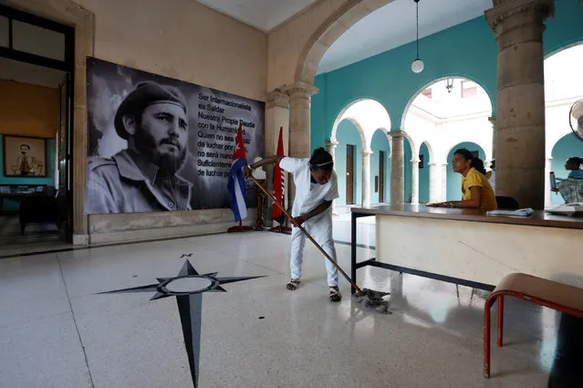 A woman cleans the floor at a municipal office and near a photograph of Cuba's former President Fidel Castro as his funeral cortege travels across the island for the final resting place of his ashes in eastern Santiago de Cuba, in Havana, Cuba, December 3, 2016. (Photo by Reuters/Stringer)
