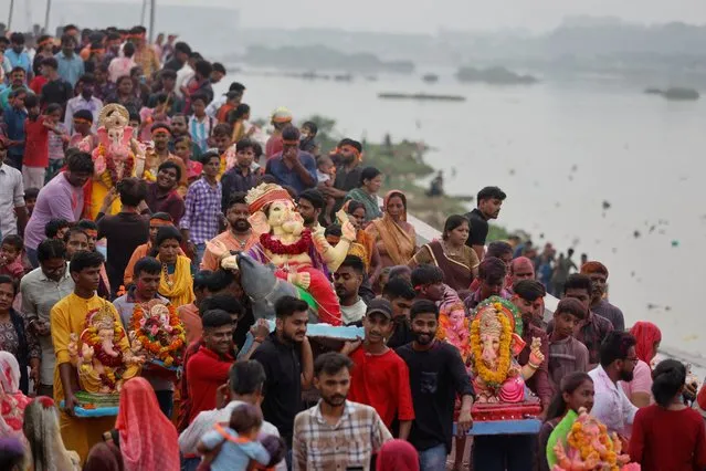 People carry an idol of the Hindu elephant god Ganesh, the deity of prosperity, for immersion into an artificial pond on the river bank of Sabarmati on the last day of the Ganesh Chaturthi Festival, in Ahmedabad, India on September 28, 2023. (Photo by Amit Dave/Reuters)