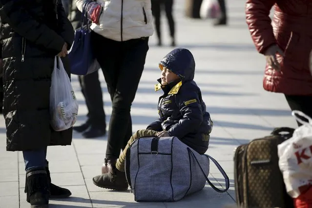Xiao Yaoyao, 6, siting on the bag reacts as he and his parents wait for their train to hometown Changde of Hunan province, at Beijing Railway station, in Beijing, China, January 25, 2016. (Photo by Jason Lee/Reuters)