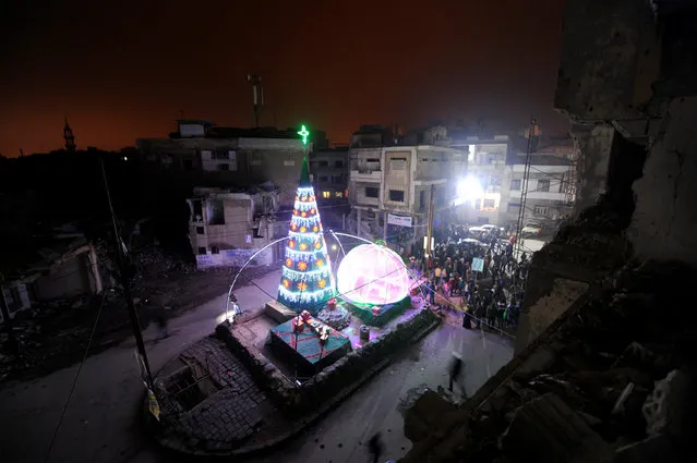 People gather by a Christmas tree near damaged buildings during Christmas eve in al-Hamidiyah neighbourhood in the old city of Homs, Syria December 24, 2016. (Photo by Omar Sanadiki/Reuters)