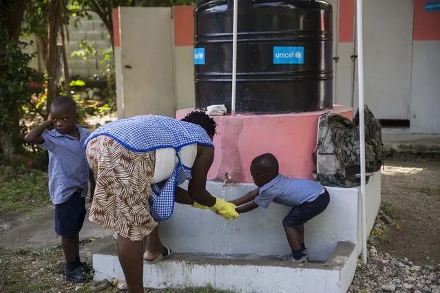 An employee teaches a child how to wash his hands as a precaution against the spread of COVID-19 at a school run by UNICEF, in Les Cayes, Haiti, Wednesday, May 27, 2021. (Photo by Joseph Odelyn/AP Photo)