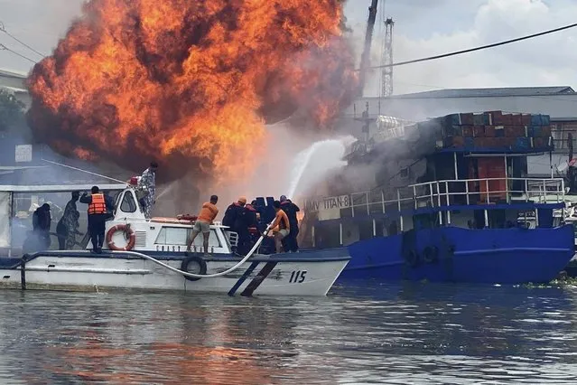 In this photo provided by the Philippine Coast Guard, members of the Philippine Coast Guard try to extinguish flames on a burning cargo ship docked in Manila, Philippines, Saturday, June 12, 2021. The fire and a powerful blast ripped through ship docked to refuel in the Philippine capital of Manila on Saturday, injuring at least six people and igniting a blaze in a nearby riverside slum that gutted dozens of shanties, officials said. (Photo by Philippine Coast Guard via AP Photo)