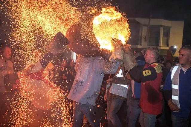 A participant runs with a burning barrel soaked in tar at the annual Ottery St Mary tar barrel festival on November 5, 2018 in Devon, England. The tradition, which is over 400 years old, sees competitors (who must have been born in the town to take part) running with burning barrels on their backs through the village, until the heat becomes too unbearable or the barrel breaks down, starting with junior barrels carried by children and continuing all evening with ever larger and larger barrels. The event, which has been threatened with closure on previous years due to increasing public liability insurance costs, raises thousands of pounds for charity and attracts spectators from around the world. (Photo by Matt Cardy/Getty Images)
