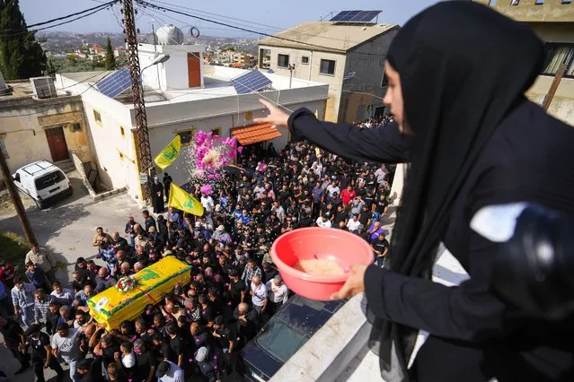 A woman throws rice and flowers as people carry the coffin of Hezbollah fighter, Bilal Nemr Rmeiti, who was killed by Israeli shelling, during his funeral procession in Majadel village, south Lebanon, Sunday, October 22, 2023. (Photo by Hassan Ammar/AP Photo)