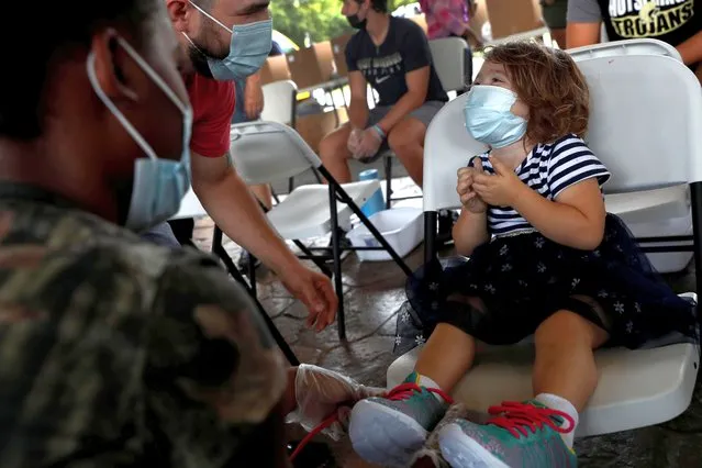 Riley Shirley, 2, smiles while wearing a protective face mask after receiving shoes at the Hot Springs Community Resource Fair that provided free coronavirus disease (COVID-19) vaccines, resources, tennis shoes, school resources and backpacks in Hot Springs, Arkansas, U.S., August 14, 2021. (Photo by Shannon Stapleton/Reuters)