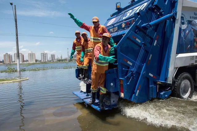 Garbage collectors pose for the picture as their truck negociates a flooded road in Vila Velha, Espirito Santo state, Brazil, on December 27, 2013. (Photo by Yasuyoshi Chiba/AFP Photo)