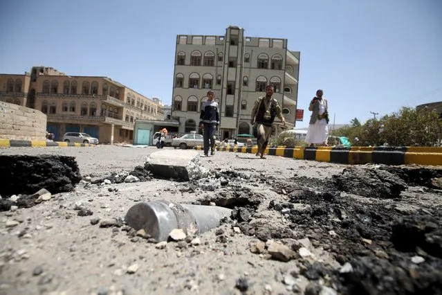 People look at an artillery shell in the ground along a damaged street, caused by an April 20 air strike that hit a nearby army weapons depot, in Sanaa April 21, 2015. (Photo by Mohamed al-Sayaghi/Reuters)