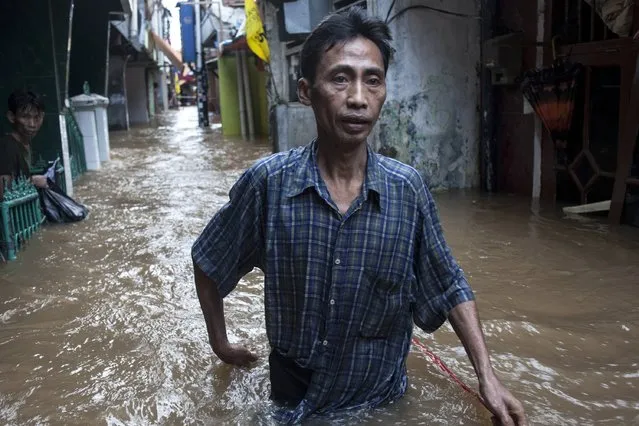 A man walks trough flooded water at Kampung pulo sub-district on January 13, 2014 in Jakarta, Indonesia. Over 5000 people have been evacuated from Jakarta as rain has battered the capital. 31 villages in 18 districts across the city have been badly affected whilst a quick response team has been deployed to aid with the evacuation. (Photo by Oscar Siagian/Getty Images)