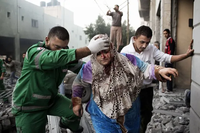 A Palestinian woman is helped by a paramedic out of her building, damaged during an Israeli air raid on a nearby sporting centre in Gaza City November 19, 2012. (Photo by Marco Longari/AFP Photo)