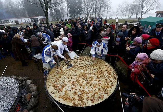 Employees cut fried dranik, a potato pancake that is the national dish of Belarus, to entertain visitors in the Sula History Park near the village of Sula, Belarus March 7, 2016. (Photo by Vasily Fedosenko/Reuters)