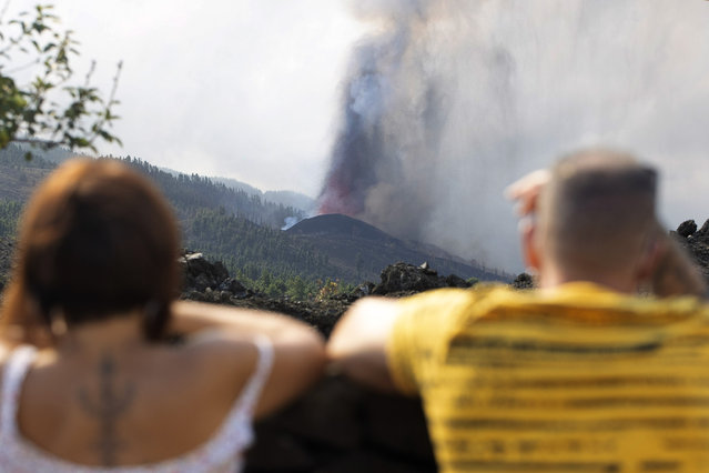 People watch as lava flows from an eruption of a volcano near El Paso on the island of La Palma in the Canaries, Spain, of Monday, September 20, 2021. Lava continues to flow slowly from a volcano that erupted in Spain's Canary Islands off northwest Africa. The head of the islands' regional government says Monday he expects no injuries to people in the area after some 5,000 were evacuated. (Photo by Gerardo Ojeda/AP Photo)