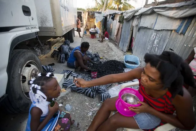 In this December 5, 2016 photo, Adrienne St. Fume fills plastic bags with charcoal in front of her shelter in the Delmas tent camp set up nearly seven years ago for people displaced by the 2010 earthquake in Port-au-Prince, Haiti. St. Fume said that unlike some of her neighbors, she would not oppose plans to move with her husband and their three children to subsidized housing for a year. (Photo by Dieu Nalio Chery/AP Photo)