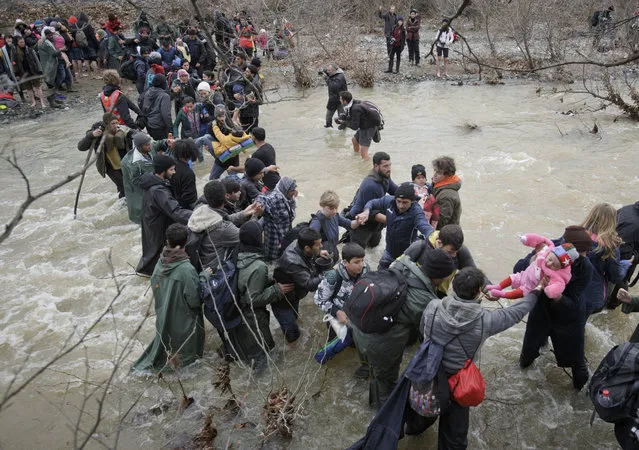 A baby is passed from hand to hand as migrants cross a river, north of Idomeni, Greece, attempting to reach Macedonia on a route that would bypass the border fence, Monday, March 14, 2016. (Photo by Vadim Ghirda/AP Photo)