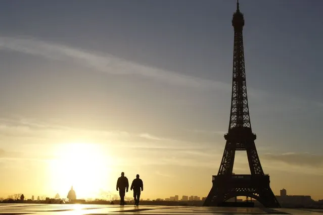 A picture taken on February 11, 2014 shows people walking at sunrise on the Trocadero Esplanade, also known as the Parvis des droits de l'homme (Parvis of Human Rights), in front of the Eiffel Tower in Paris. (Photo by Ludovic Marin/AFP Photo)