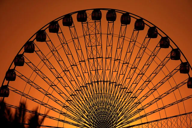 The sun sets while people enjoy a ride at an amusement park in Baghdad, Iraq, Thursday, October 21, 2021. (Photo by Hadi Mizban/AP Photo)