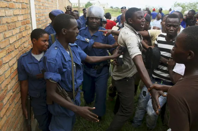 A female police officer accused of shooting a protester stands protected by fellow police officers in the Buterere neighbourhood of Bujumbura, Burundi, May 12, 2015. (Photo by Goran Tomasevic/Reuters)