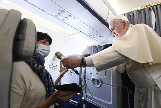 A handout picture provided by the Vatican Media shows Pope Francis handing the micriophone back to a journalist aboard the papal plane on his flight back to Rome after visiting Cyprus and Greece, 06 December 2021. (Photo by Vatican Media Handout/EPA/EFE)