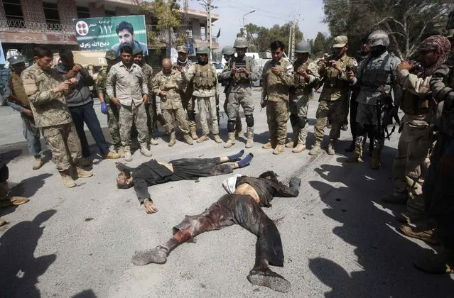 Afghan security forces stand on the corpses of Taliban insurgents after a suicide car bomb attack in Jalalabad, on March 20, 2014. (Photo by Reuters/Parwiz)