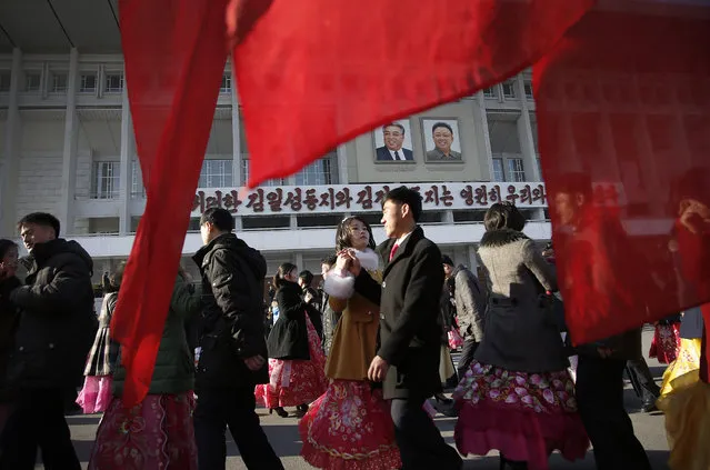 North Korean men and women participate in a mass dance party at the Pyongyang Indoor Stadium where the portraits of late leaders Kim Il Sung, left, and Kim Jong Il, right, hang at the entrance as part of celebrations of the “Day of the Shining Star” or birthday anniversary of Kim Jong Il on Tuesday, February 16, 2016, in Pyongyang, North Korea. (Photo by Wong Maye-E/AP Photo)