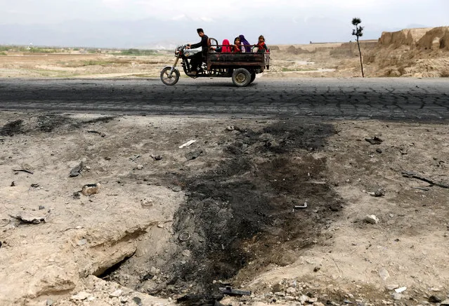 An Afghan family ride on a bike past the site of a car bomb attack where U.S. soldiers were killed near Bagram air base, Afghanistan on April 9, 2019. (Photo by Mohammad Ismail/Reuters)