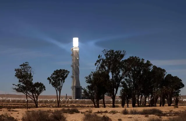 A view of the solar tower of Israel's Ashalim power station, a solar power station in the Negev desert near the kibbutz of Ashalim, on June 8, 2021. The 240-meter tower is part of a 121-megawatt solar thermal power plant which concentrates the sun's heat from thousands of small mirrors onto a boiler mounted on the tower, the latter producing high-temperature steam used to generate electricity. (Photo by Emmanuel Dunand/AFP Photo)