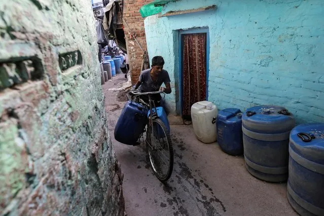 A man carries containers filled with drinking water on his cycle after fetching it from a municipal tanker in New Delhi, June 14, 2019. (Photo by Anushree Fadnavis/Reuters)