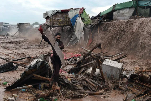 Flood waters rush through a Pakistani market area as a man tries to salvage materials on the outskirts of Peshawar on April 3, 2016. Heavy rains have killed at least 121 people, injured 124 and damaged 852 houses since March 9 across Pakistan, according to the National Disaster Management Authority. It said landslides and collapsed roofs caused most of the fatalities. (Photo by A. Majeed/AFP Photo)