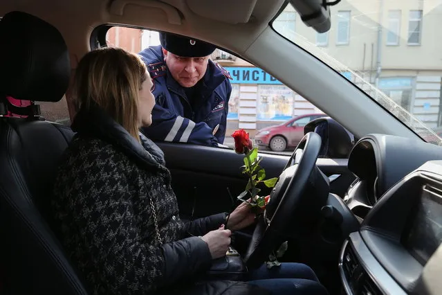 A traffic policeman congratulates a female driver on upcoming International Women's Day in Ryazan, Russia on March 7, 2017. (Photo by Alexander Ryumin/TASS via Getty Images)