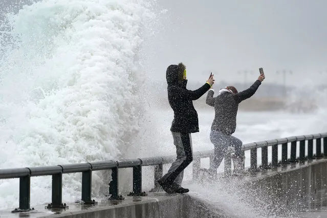 Two women jump off a seawall as they photograph rough surf along Lynn Shore Reservation in the aftermath of a snowstorm, Tuesday, February 2, 2021, in Lynn, Mass. A sprawling, lumbering winter storm has walloped the Eastern U.S., shutting down coronavirus vaccination sites, closing schools and halting transit. (Photo by Elise Amendola/AP Photo)